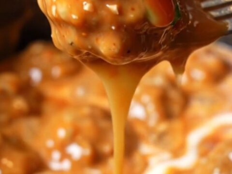 A close-up shot of creamy Bang Bang chicken meatballs in a white slow cooker