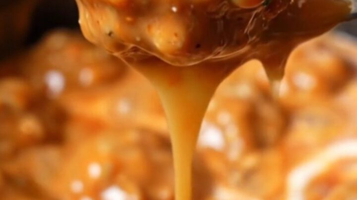 A close-up shot of creamy Bang Bang chicken meatballs in a white slow cooker