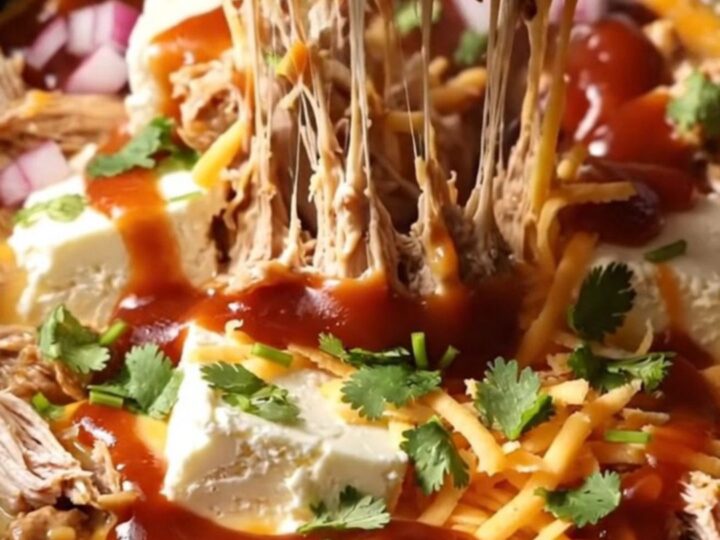 A dark bronze ceramic slow cooker filled with creamy BBQ pulled chicken dip topped with cilantro.