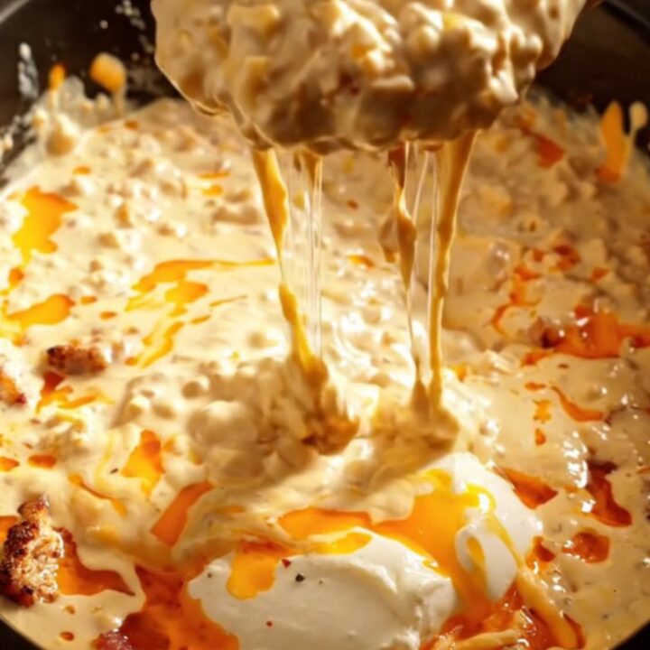 A warm ceramic Crockpot filled with creamy Cajun Blackened Chicken and Pepper Jack dip on a rustic kitchen counter.