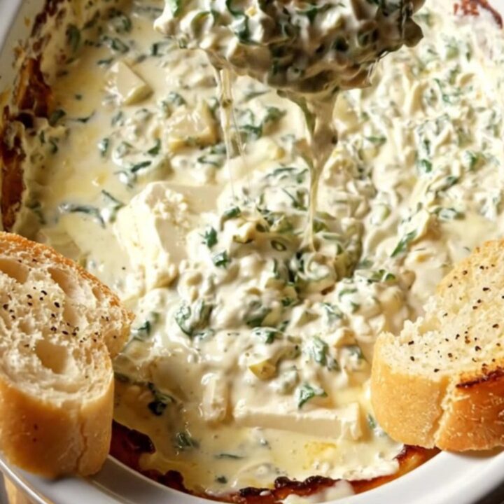 A close-up of a toasted baguette slice being dipped into a creamy