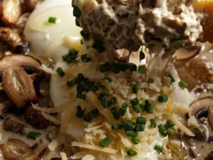 A close-up of a creamy wild mushroom and Gruyere dip in a ceramic Crockpot, garnished with truffle oil and fresh chives.