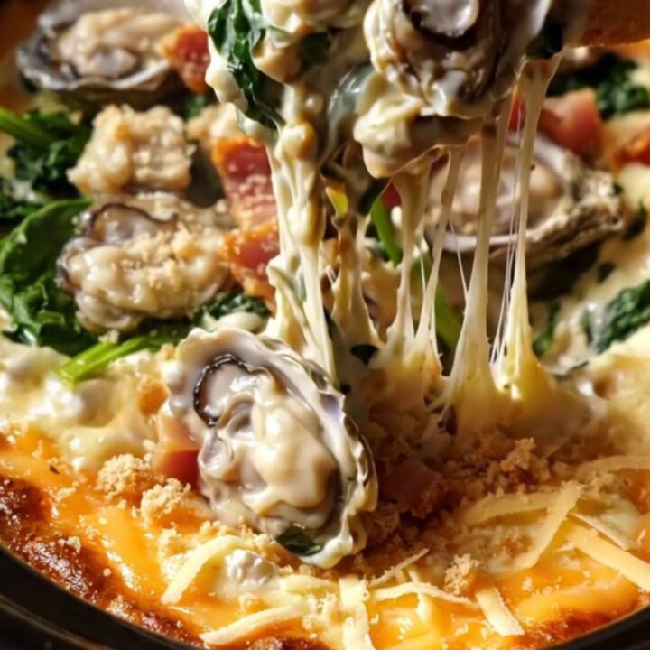 A creamy, bubbling Oysters Rockefeller dip in a black ceramic slow cooker, topped with crispy breadcrumbs.