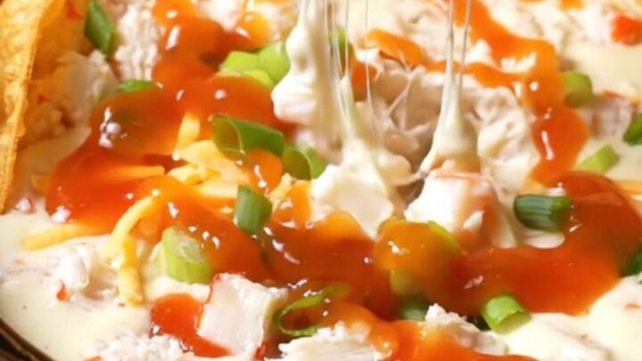A glossy black slow cooker filled with creamy crab rangoon dip