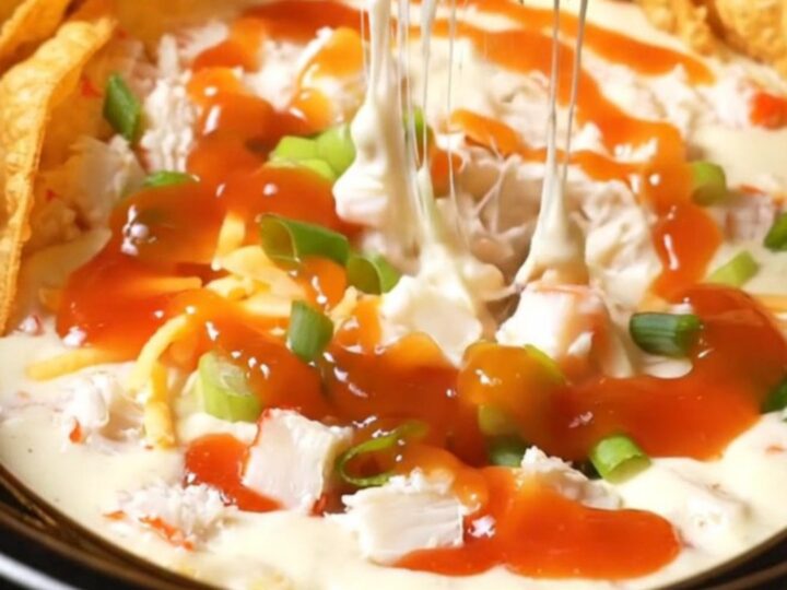 A glossy black slow cooker filled with creamy crab rangoon dip