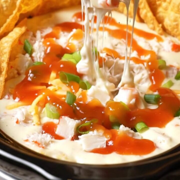 A glossy black slow cooker filled with creamy crab rangoon dip