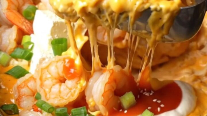 Creamy Bang Bang shrimp dip in a black ceramic slow cooker, topped with crispy shrimp, scallions, and sesame seeds.
