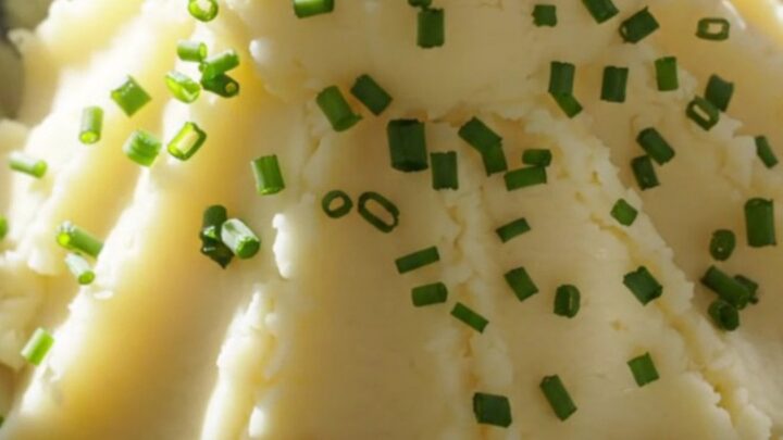 A close-up view of velvety mashed potatoes in a cream-colored stoneware slow cooker