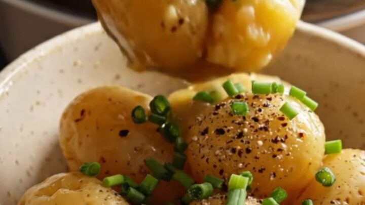 A close-up of glossy, fork-tender baby potatoes in a slow cooker