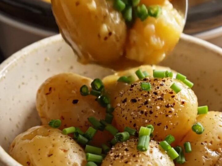 A close-up of glossy, fork-tender baby potatoes in a slow cooker