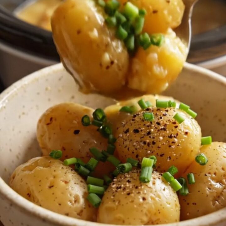 A close-up of glossy, fork-tender baby potatoes in a slow cooker