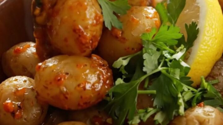 A rustic bowl filled with steaming Cajun garlic butter red potatoes garnished with fresh parsley and lemon.