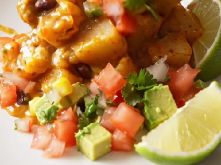 A steaming scoop of smoky chipotle cheddar fiesta potatoes topped with fresh cilantro and avocado in a rustic bowl.