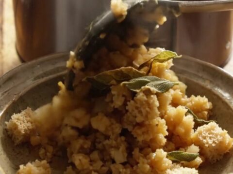 A close-up of golden, herb-infused sourdough stuffing in a navy-blue ceramic slow cooker.