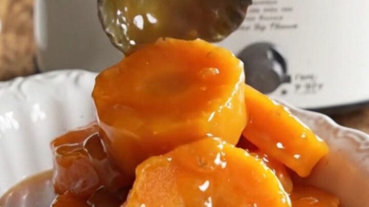 A close-up of tender, caramelized garnet yam medallions in a vintage ceramic slow cooker with bubbling brown sugar syrup.