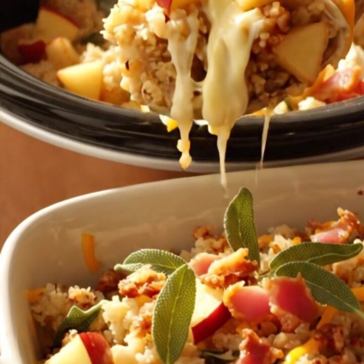 A close-up of slow-cooker stuffing in a ceramic dish, featuring visible sourdough cubes, melted white cheddar