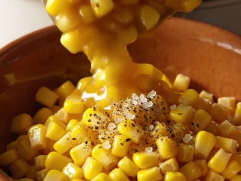 A warm bowl of creamy slow cooker honey butter corn topped with cracked black pepper.