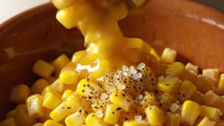 A warm bowl of creamy slow cooker honey butter corn topped with cracked black pepper.