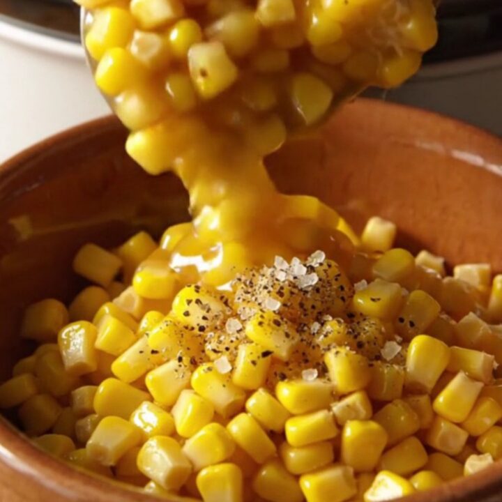 A warm bowl of creamy slow cooker honey butter corn topped with cracked black pepper.