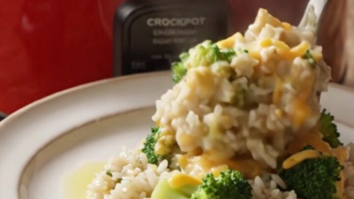 A steaming bowl of creamy broccoli and rice casserole topped with golden, buttery cracker crumbs and melted cheddar cheese.