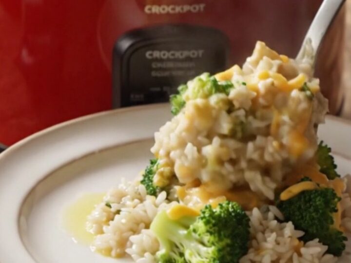 A steaming bowl of creamy broccoli and rice casserole topped with golden, buttery cracker crumbs and melted cheddar cheese.