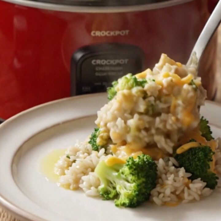 A steaming bowl of creamy broccoli and rice casserole topped with golden, buttery cracker crumbs and melted cheddar cheese.