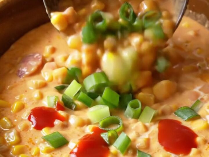 A warm, rustic bowl filled with creamy Cajun maque choux, featuring bright corn kernels, bits of sausage, and peppers.