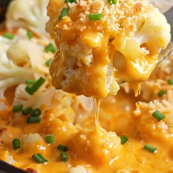 A close-up shot of a bubbling Crockpot cauliflower au gratin with a dramatic cheese pull, showing melted Gruyère and cheddar.