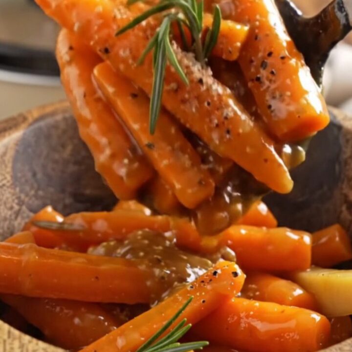 A rustic bowl filled with glossy, caramelized maple Dijon carrots and parsnips garnished with fresh rosemary.