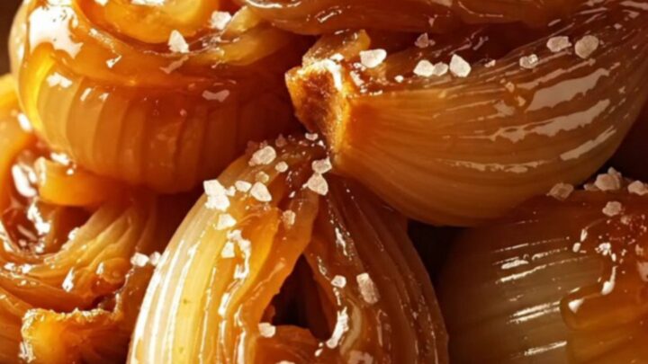A warm platter of glossy, mahogany-glazed cipollini onions garnished with fresh thyme sprigs.