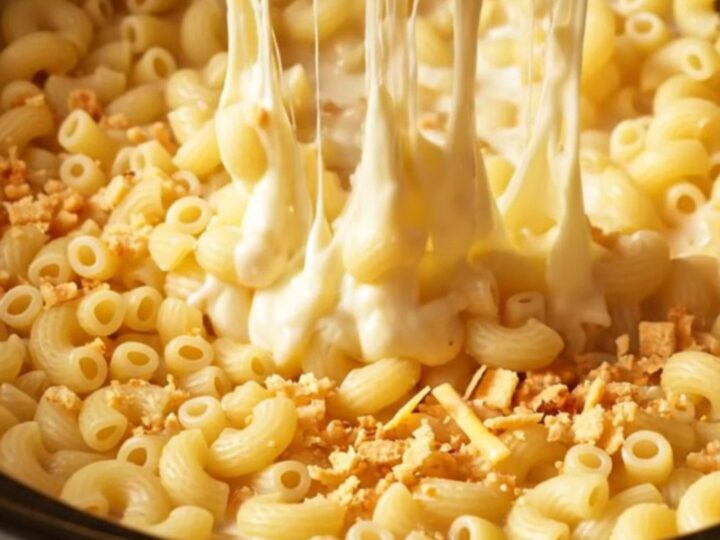 A close-up of a steaming bowl of five-cheese mac and cheese with a dramatic cheese pull.