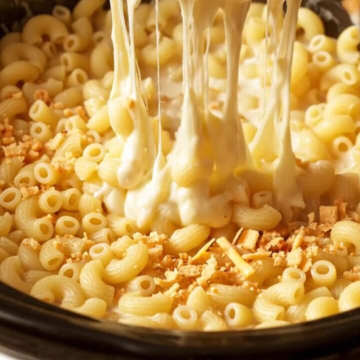 A close-up of a steaming bowl of five-cheese mac and cheese with a dramatic cheese pull.