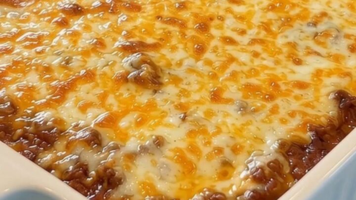A spatula lifting a massive, steaming cheese pull of melted golden mozzarella over rich meat sauce pasta.