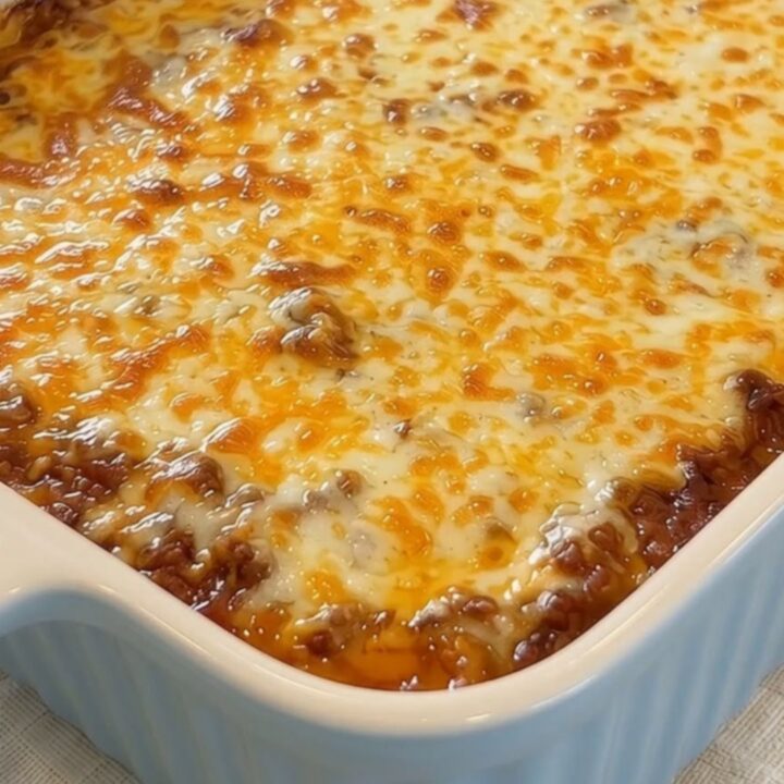 A spatula lifting a massive, steaming cheese pull of melted golden mozzarella over rich meat sauce pasta.