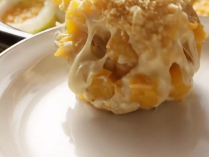 A close-up of a creamy Southern yellow squash casserole in a ceramic crockpot with a golden, buttery Ritz cracker topping.