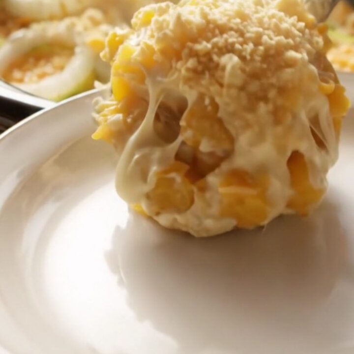 A close-up of a creamy Southern yellow squash casserole in a ceramic crockpot with a golden, buttery Ritz cracker topping.