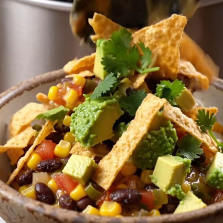 A close-up shot of a loaded fiesta corn and black bean casserole in a slow cooker with steam rising.