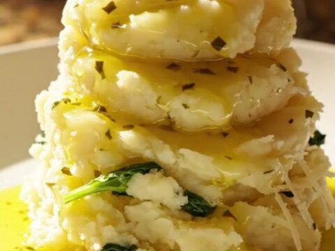 A vibrant bowl of creamy Tuscan mashed potatoes topped with sun-dried tomatoes and fresh baby spinach.