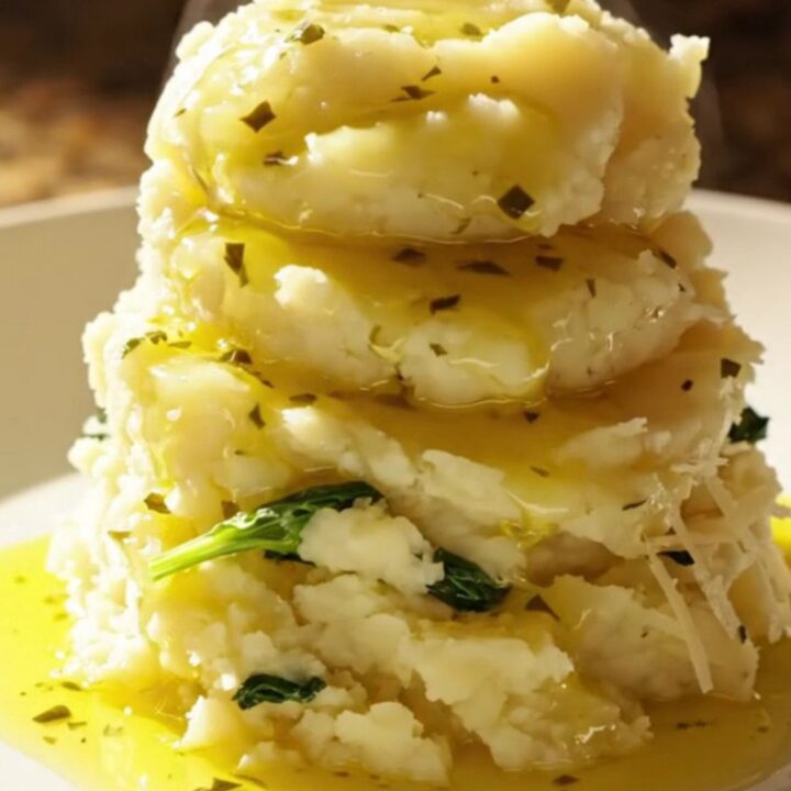A vibrant bowl of creamy Tuscan mashed potatoes topped with sun-dried tomatoes and fresh baby spinach.