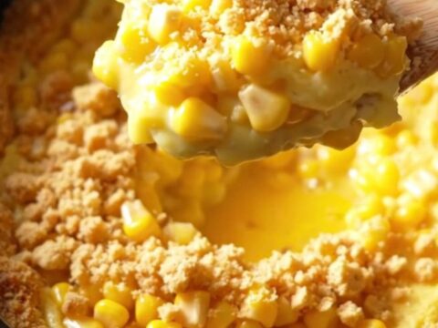 A golden, creamy Amish scalloped corn casserole in a vintage cream ceramic slow cooker with a buttery cracker crust.