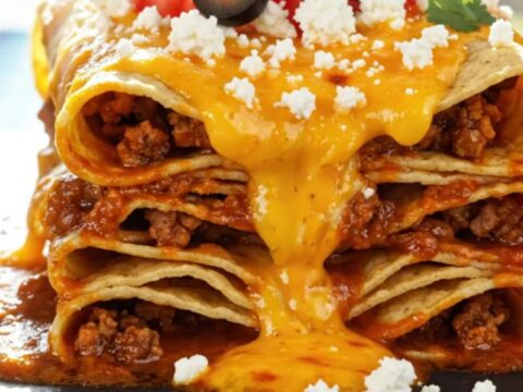 A steaming square portion of the black bean and corn enchilada stack on a matte slate plate, garnished with fresh cilantro.