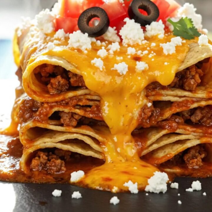 A steaming square portion of the black bean and corn enchilada stack on a matte slate plate, garnished with fresh cilantro.