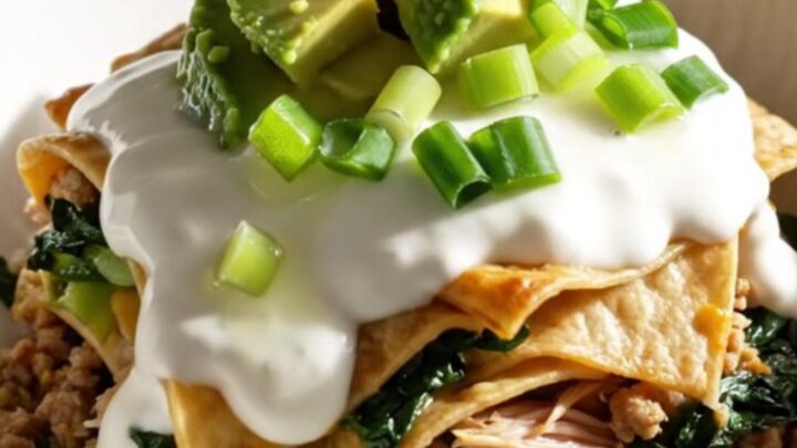 A close-up view of the bubbling, cheesy turkey enchilada bake in a sage-green slow cooker.