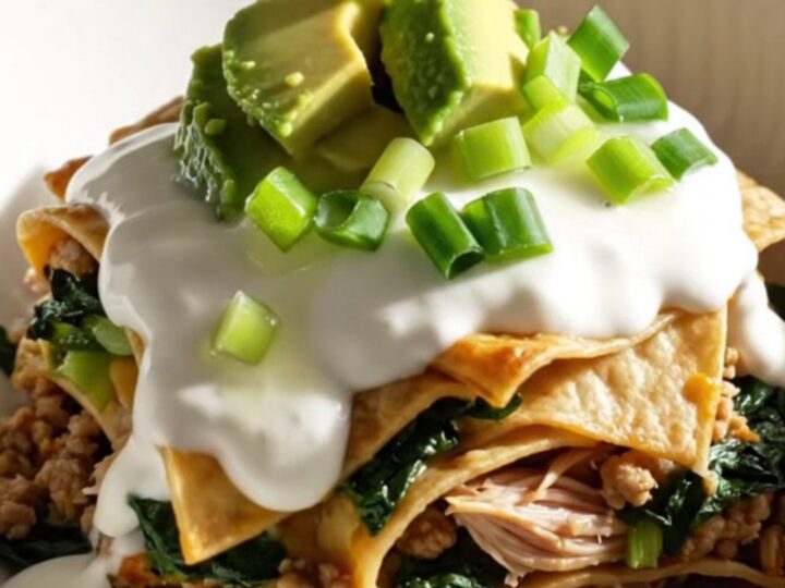 A close-up view of the bubbling, cheesy turkey enchilada bake in a sage-green slow cooker.