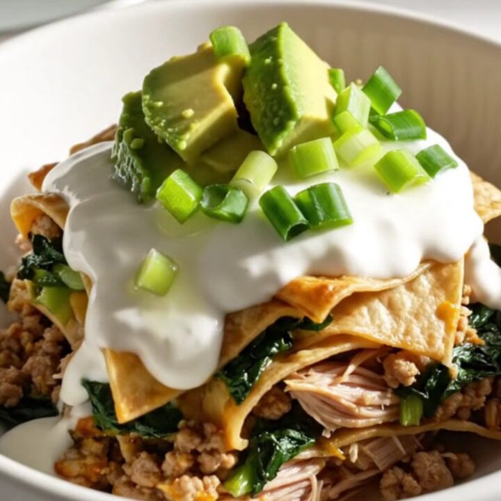 A close-up view of the bubbling, cheesy turkey enchilada bake in a sage-green slow cooker.