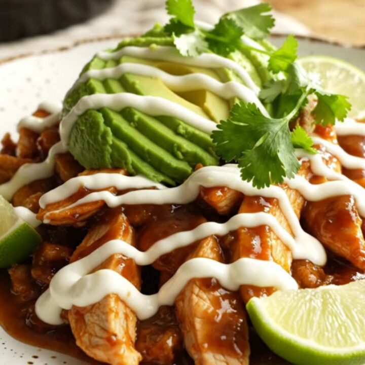 A close-up of slow-cooked chicken fajitas with mango, peppers, and melted cheese in a glossy orange pot.