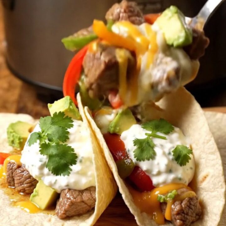 A rustic slow cooker filled with tender steak bites, colorful peppers, and melted pepper jack cheese.