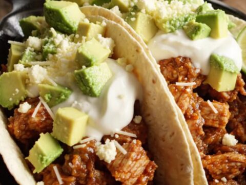 A close-up of a slow cooker filled with chicken and chorizo fajitas topped with melted cheese.