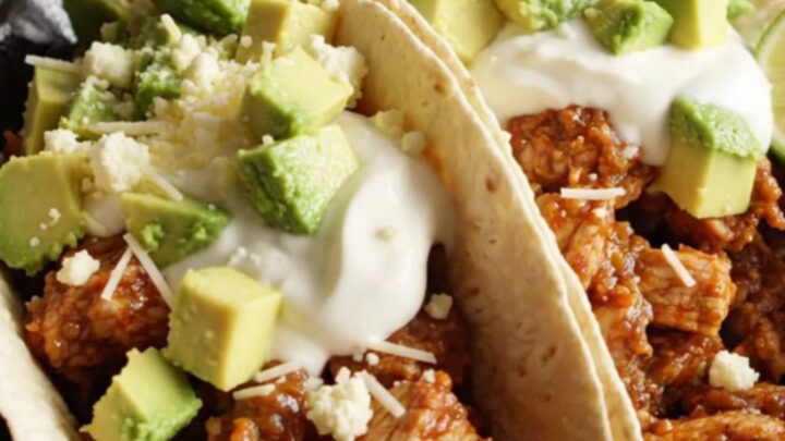 A close-up of a slow cooker filled with chicken and chorizo fajitas topped with melted cheese.