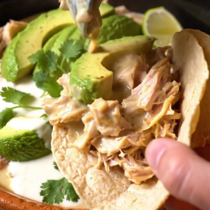 A rustic slow cooker filled with shredded chicken, roasted poblano strips, and a creamy, cheesy sauce.